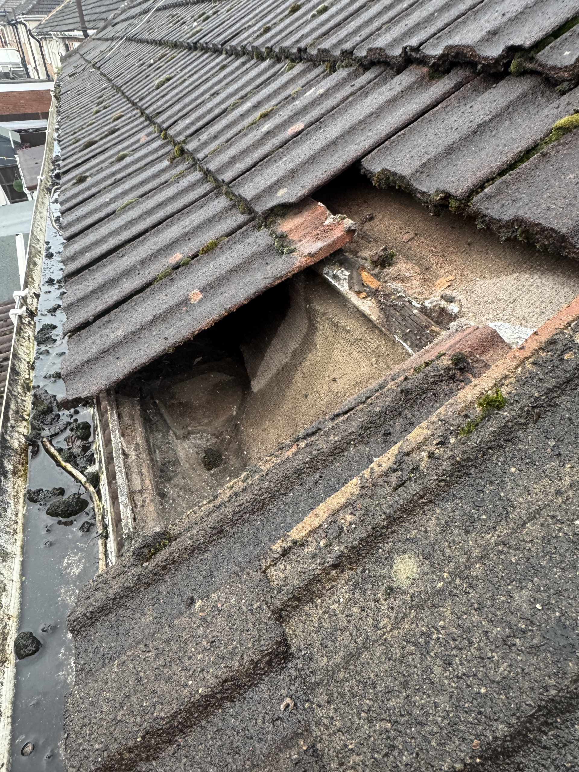 Lifted roof tiles near a gutter line